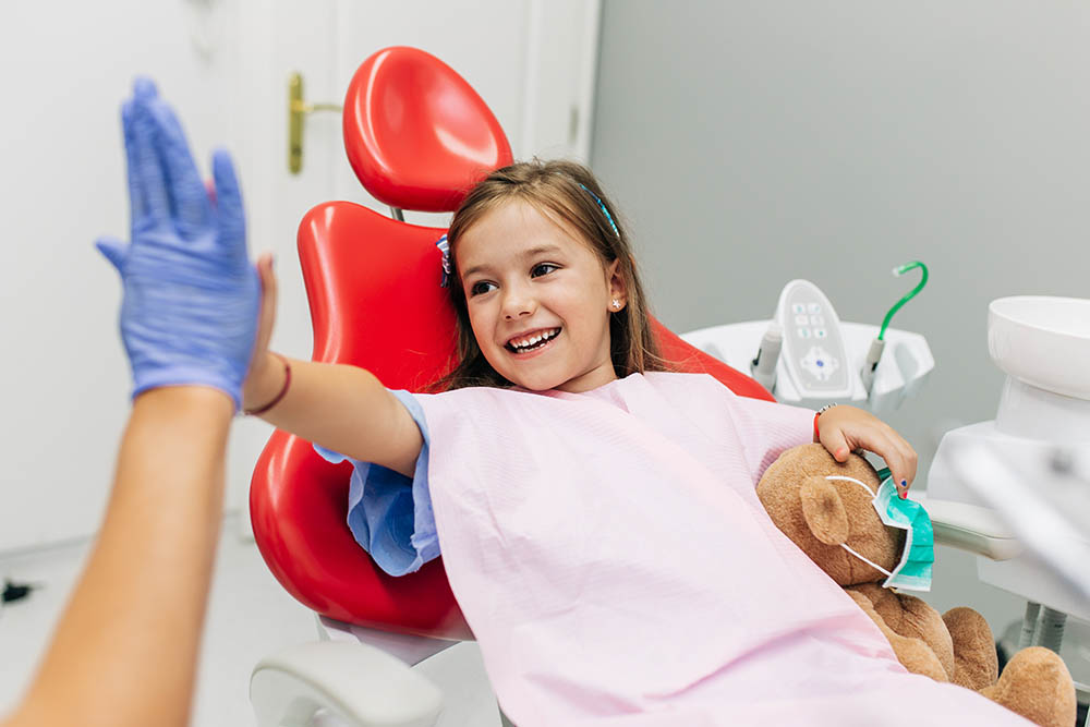 Cute little girl sitting on dental chair and having dental treatment.