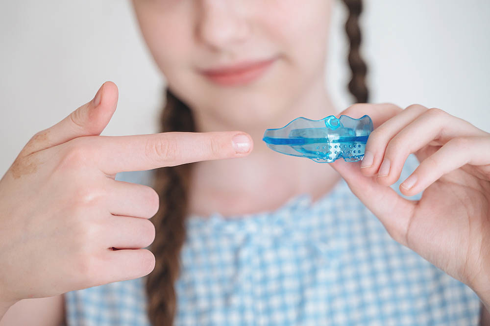 Little girl holding a flexible dental alignment mouthguard for correct bite, pediatric orthodontics routine