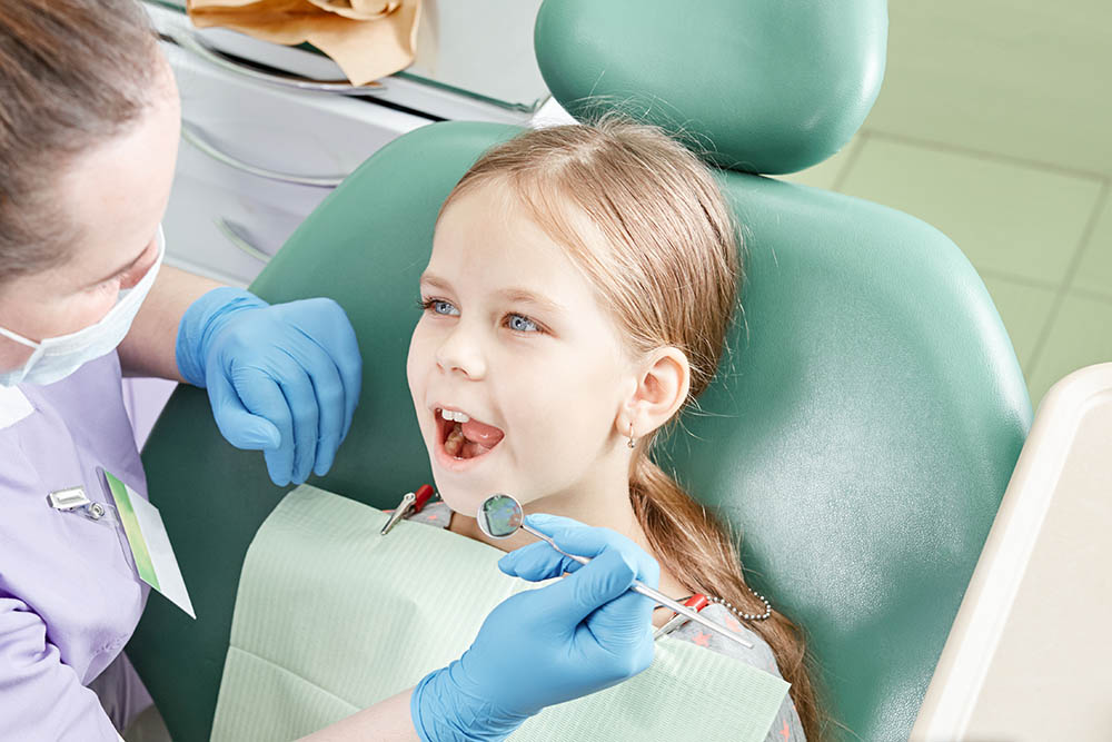 Child to the dentist. Child in the dental chair dental treatment during surgery. Small patient visiting specialist in dental clinic.
